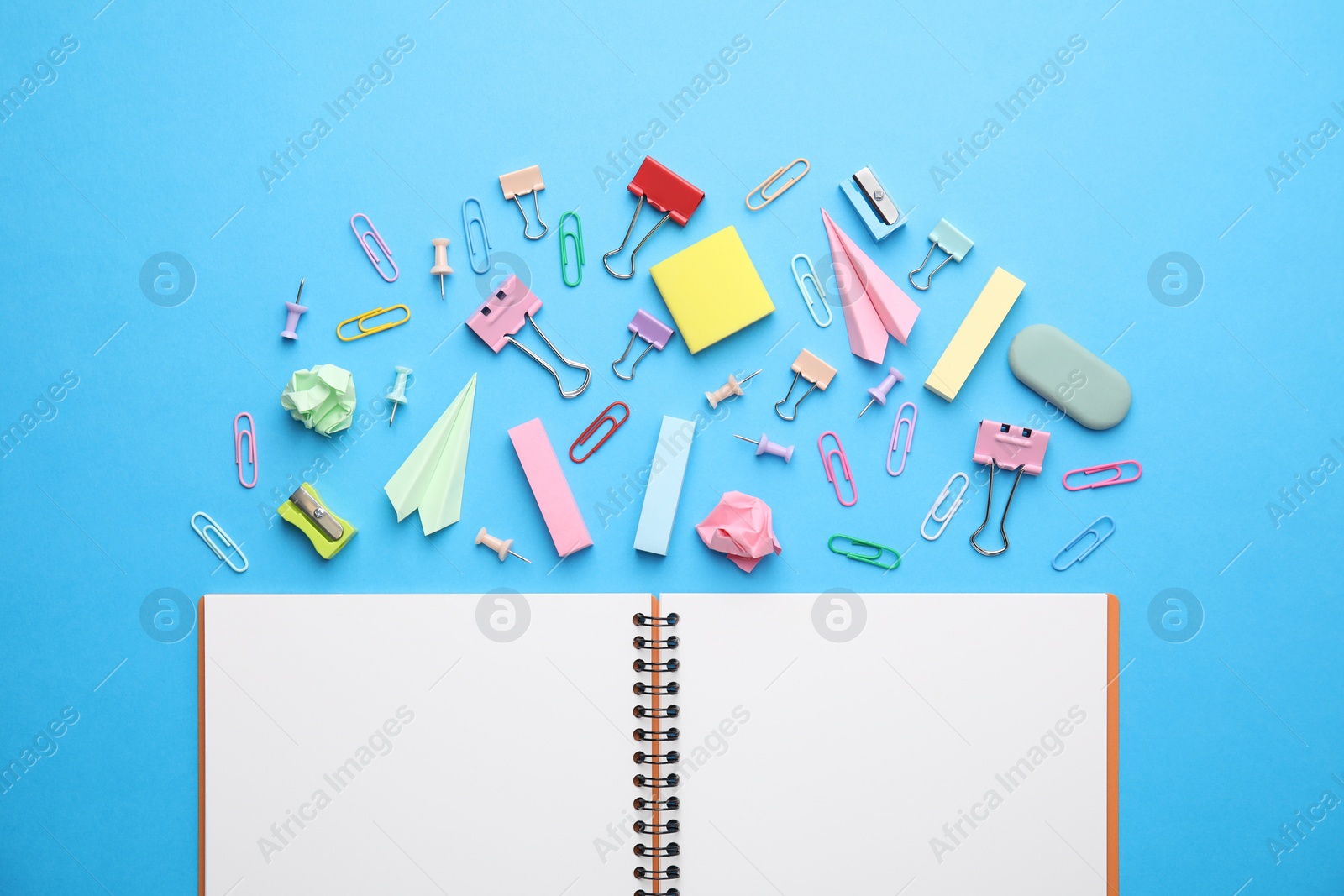 Photo of Back to school. School stationery and paper planes near notebook on light blue background, flat lay