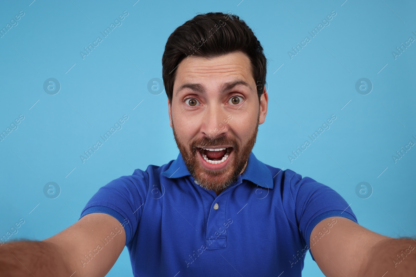 Photo of Happy man taking selfie on light blue background