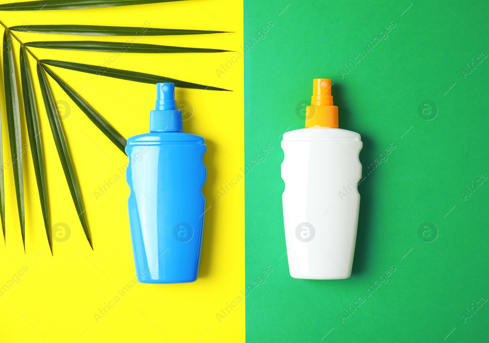 Photo of Bottles with sun protection products and tropical leaf on color background, top view