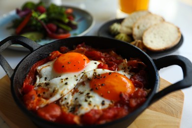 Photo of Tasty Shakshouka served in pan on table, closeup