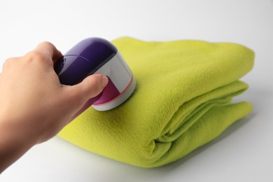 Photo of Woman cleaning woolen cloth with fabric shaver on white background, closeup