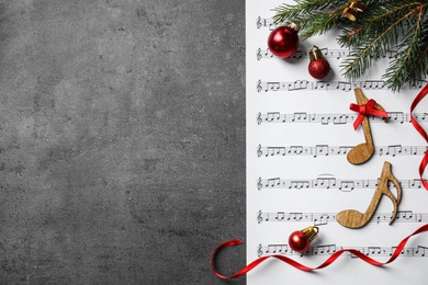 Christmas decorations, notes and music sheet on grey stone table, flat lay with space for text