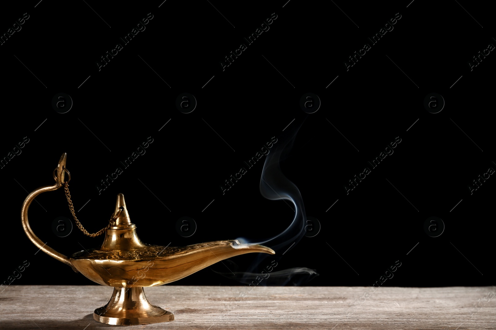 Photo of Aladdin magic lamp on table against black background