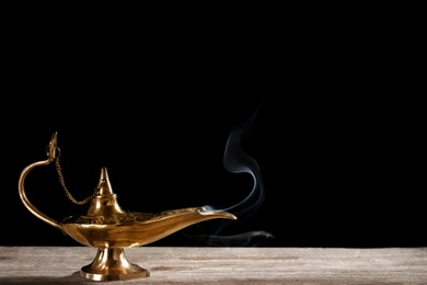 Aladdin magic lamp on table against black background
