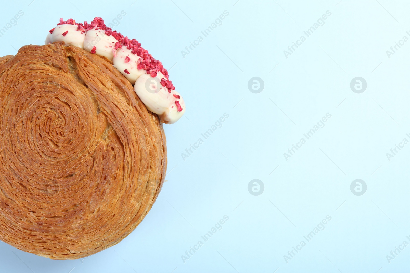 Photo of One supreme croissant with cream on light blue background, top view with space for text. Tasty puff pastry