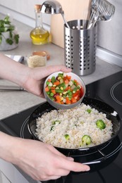 Photo of Woman cooking tasty rice with vegetables on induction stove, closeup