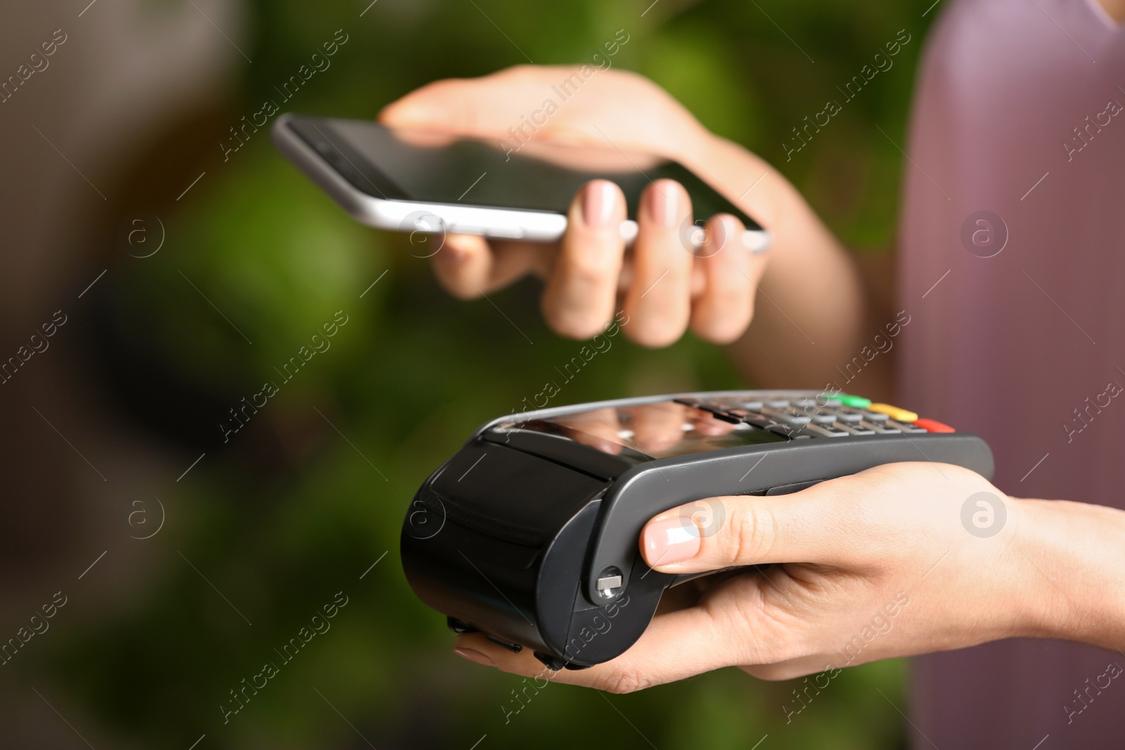 Photo of Woman using modern payment terminal with mobile phone indoors, closeup