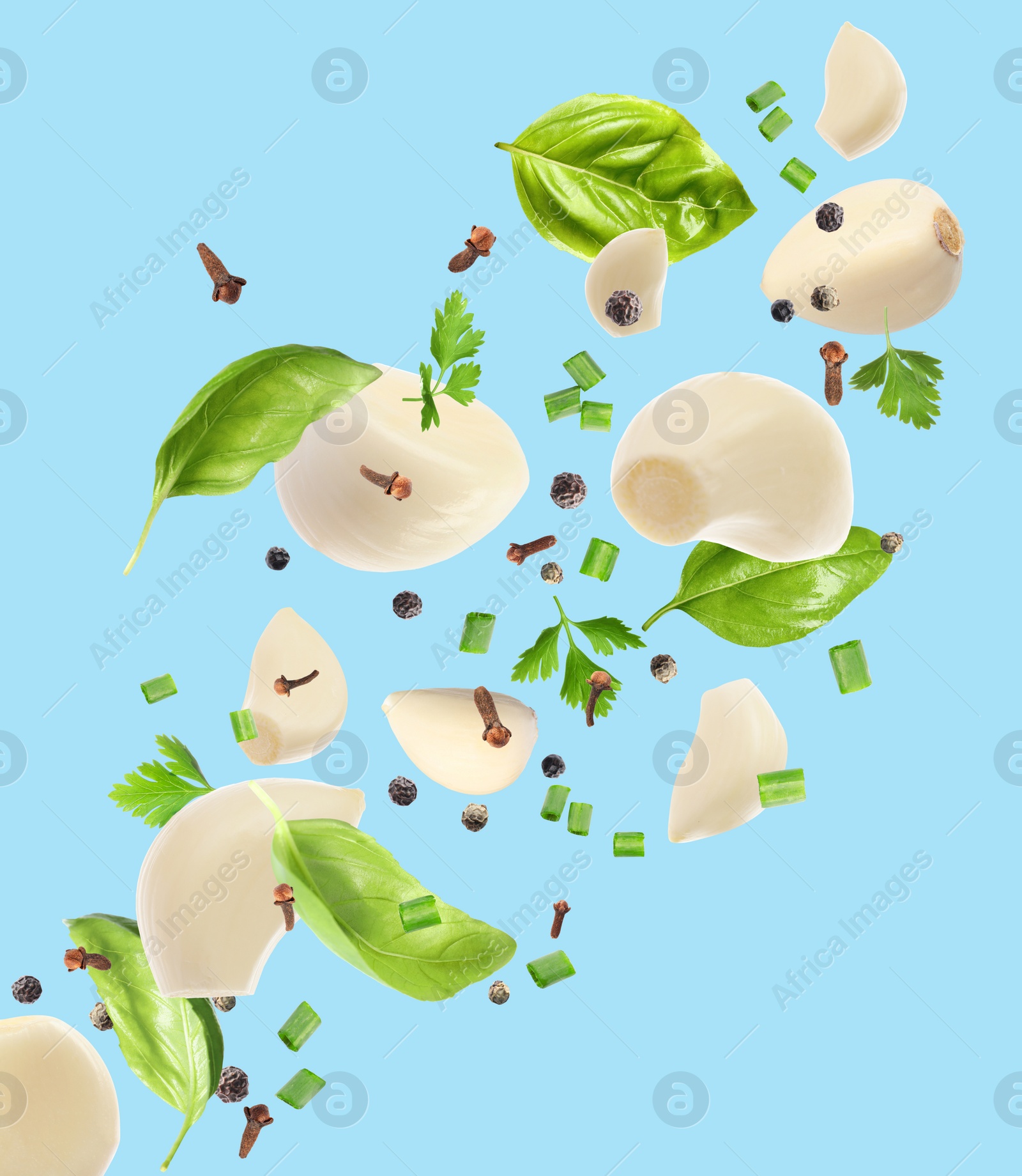 Image of Fresh peeled garlic cloves, peppercorns and different herbs flying on light blue background