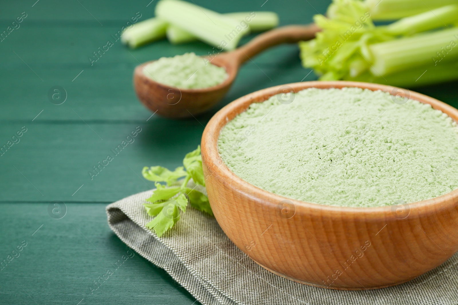 Photo of Natural celery powder and fresh stalks on green wooden table, closeup. Space for text
