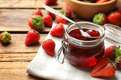 Photo of Delicious pickled strawberry jam and fresh berries on wooden table