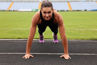 Photo of Young woman doing high plank exercise at stadium