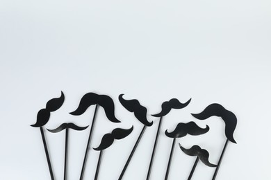 Fake paper mustaches party props on light background, flat lay. Space for text