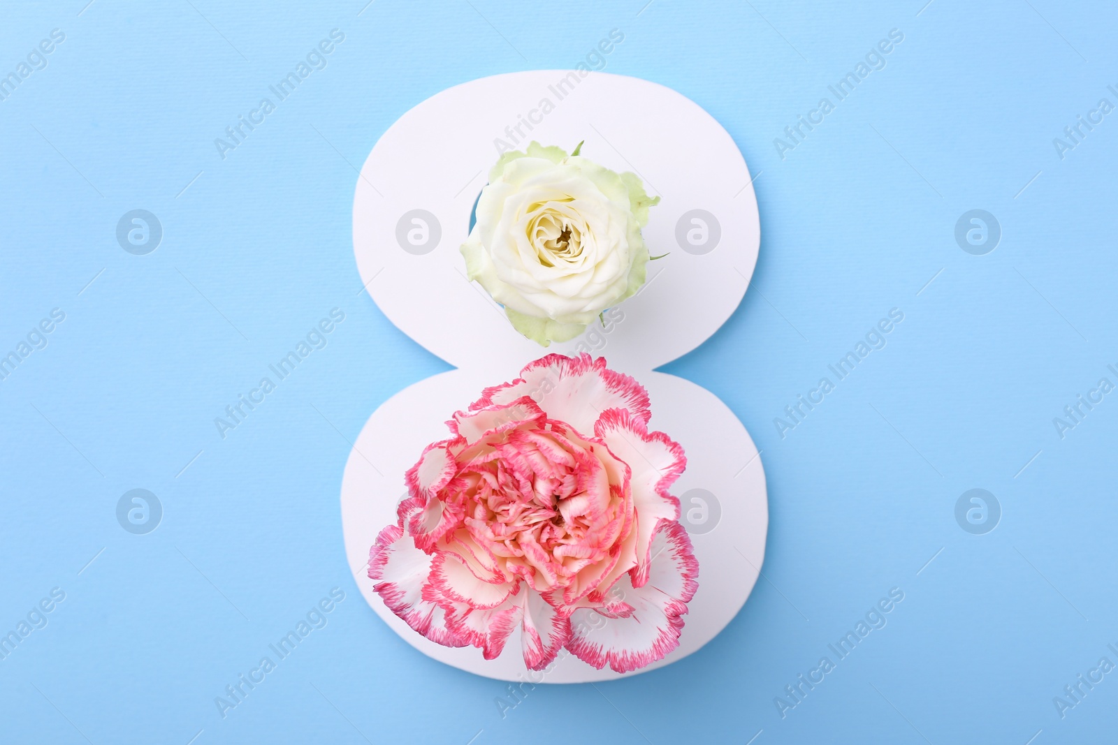 Photo of Paper number 8 and beautiful flowers on light blue background, top view