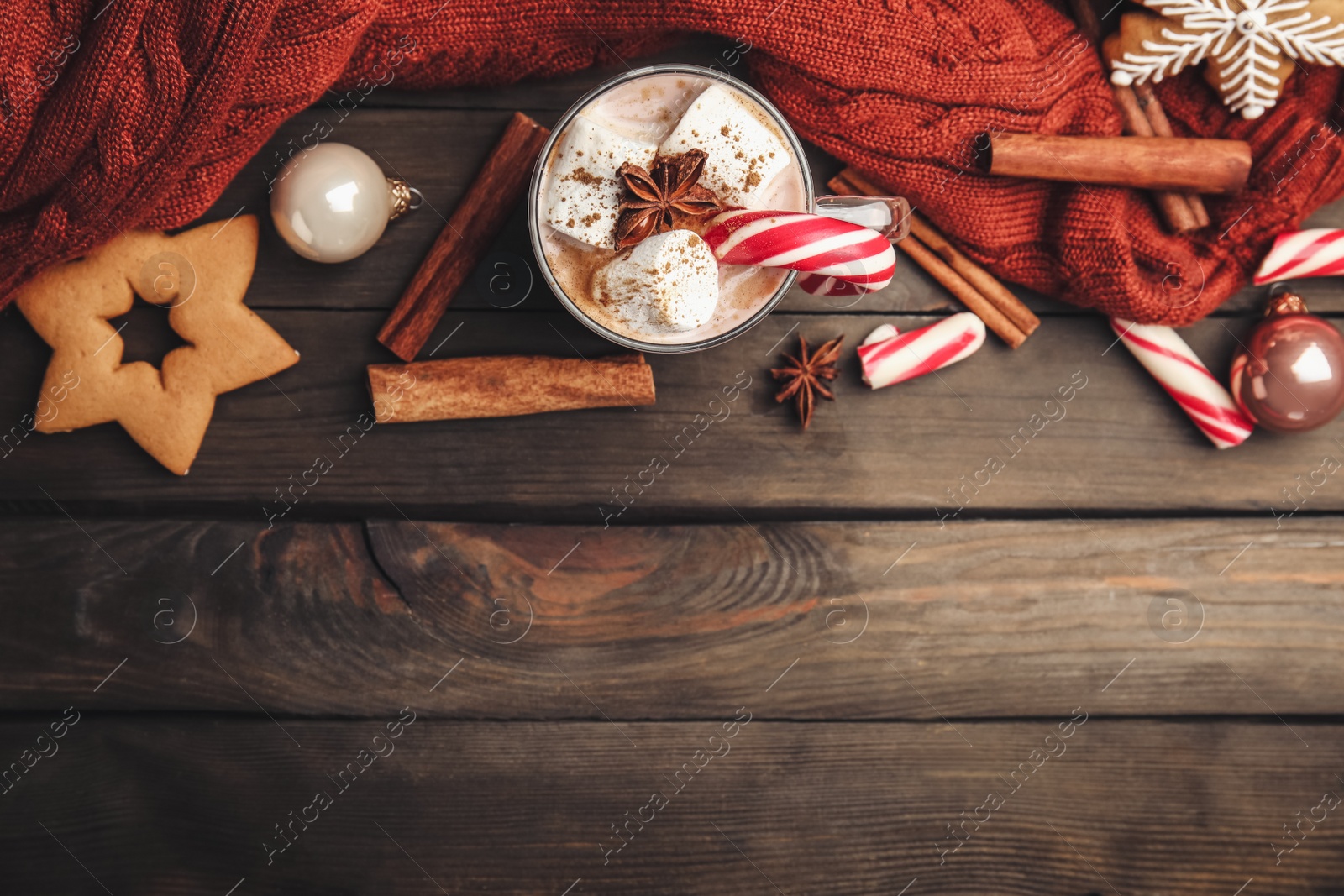 Photo of Flat lay composition with glass cup of tasty cocoa and Christmas candy cane on wooden table. Space for text