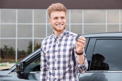 Photo of Attractive young man with key near luxury car outdoors
