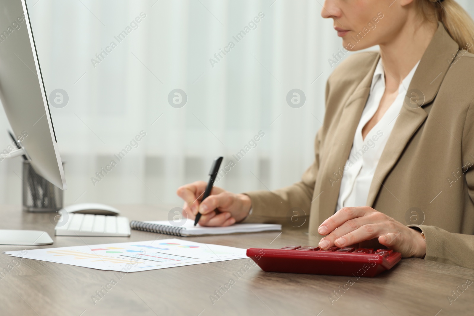 Photo of Professional accountant using calculator at wooden desk in office, closeup