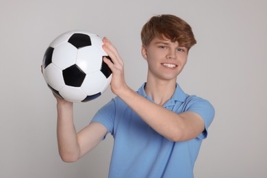 Teenage boy with soccer ball on light grey background