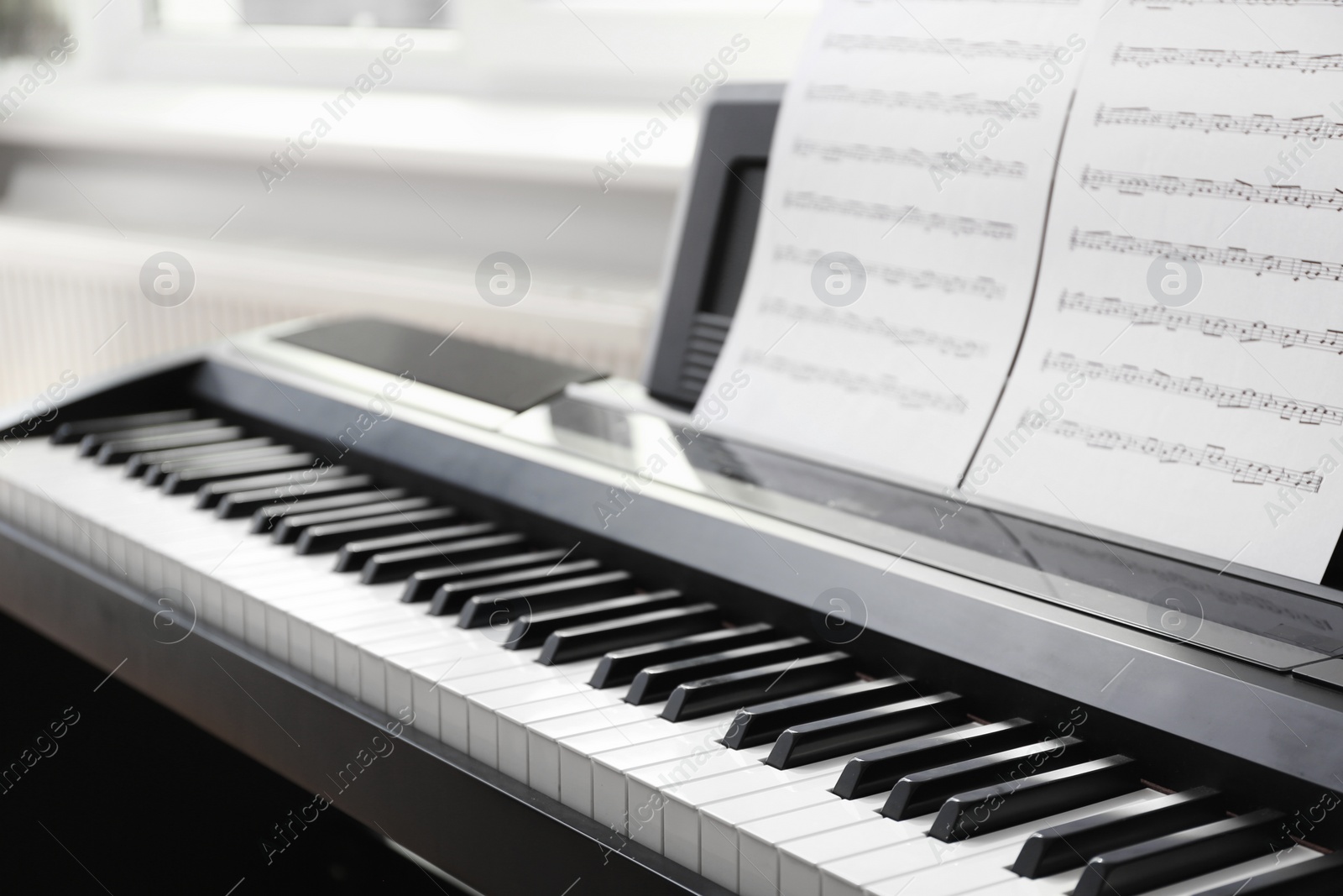 Photo of Modern piano with music sheets in room, closeup