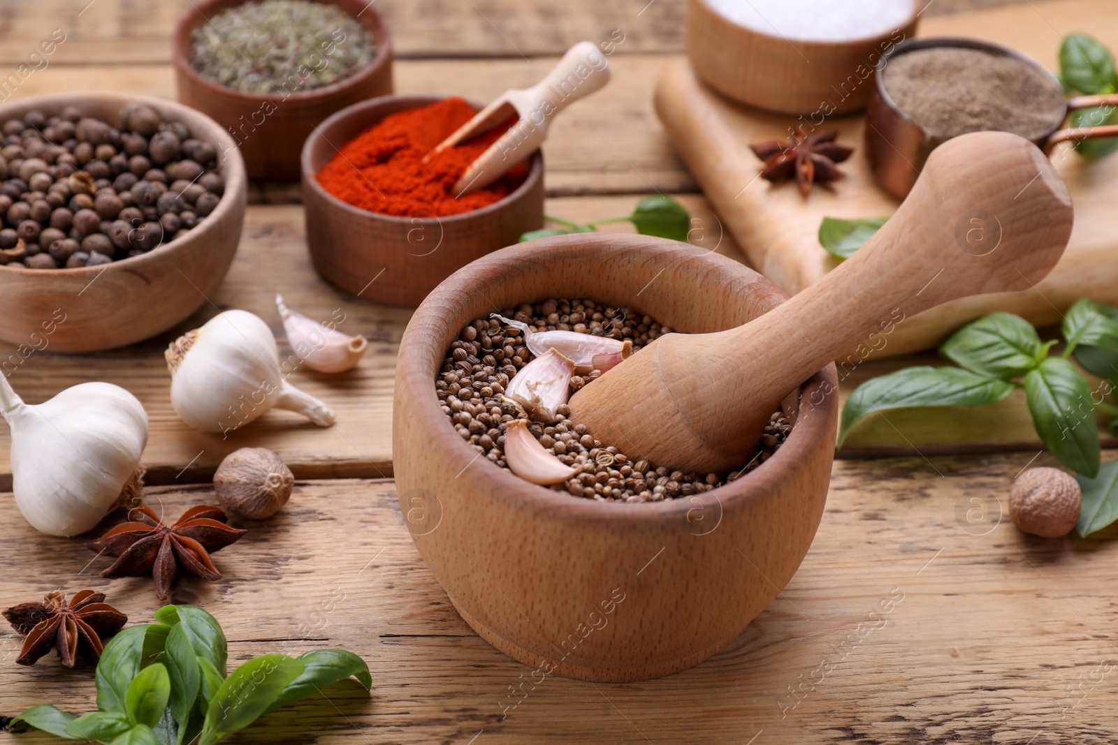 Photo of Mortar with pestle and different spices on wooden table