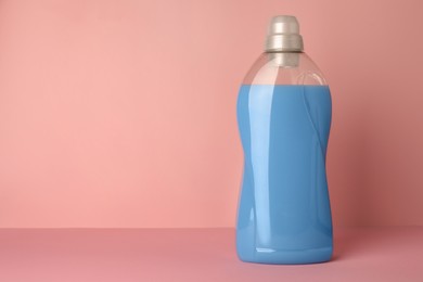 Photo of Bottle of fabric softener on pink background, space for text