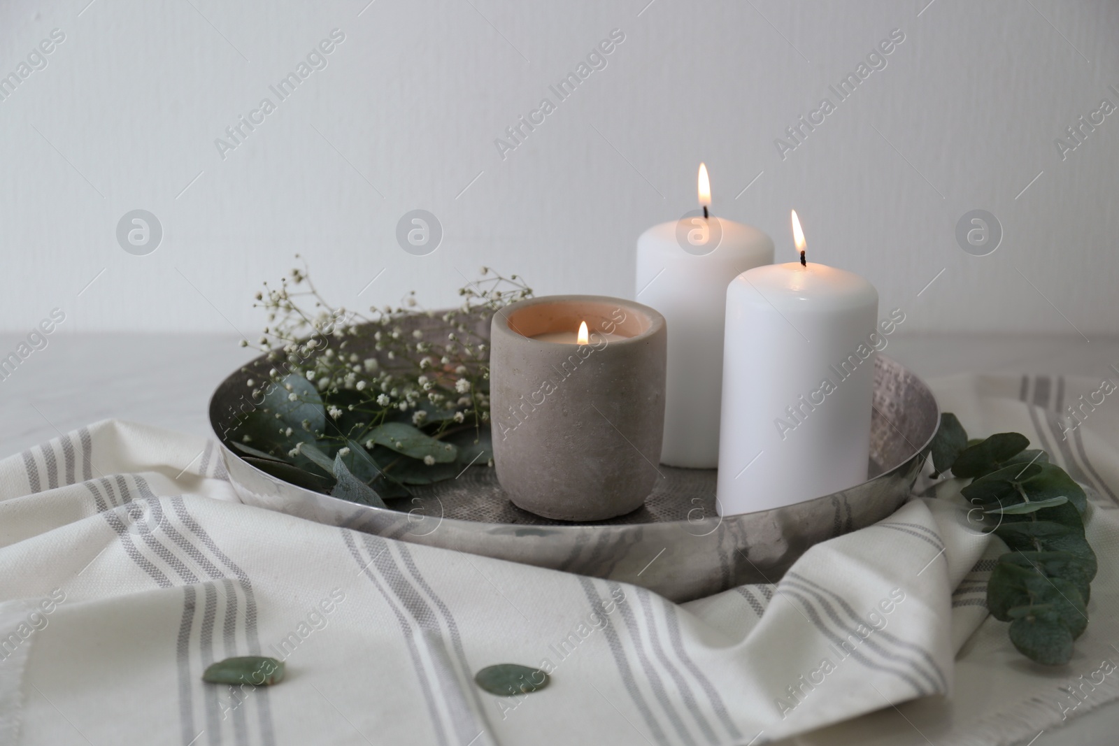 Photo of Beautiful eucalyptus branches, flowers and burning candles on table. Interior element