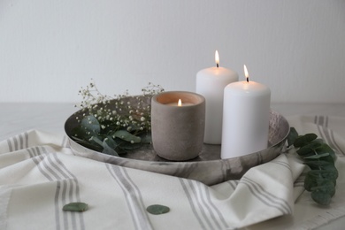 Photo of Beautiful eucalyptus branches, flowers and burning candles on table. Interior element