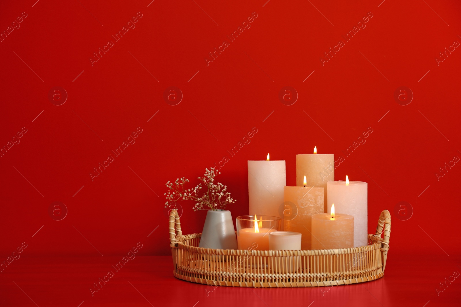 Photo of Tray with burning candles on red background. Space for text