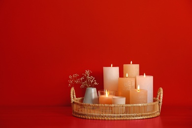 Photo of Tray with burning candles on red background. Space for text