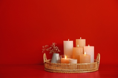 Tray with burning candles on red background. Space for text