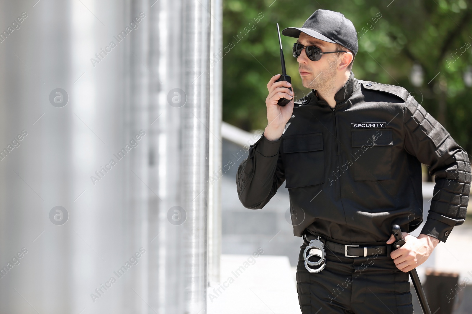 Photo of Male security guard using portable radio transmitter outdoors