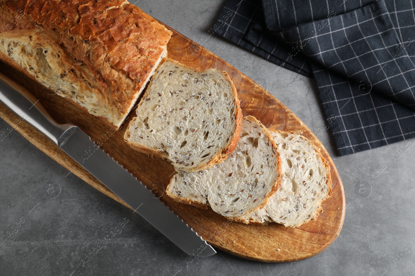 Photo of Freshly baked cut sourdough bread and knife on grey table, top view