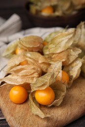 Photo of Ripe physalis fruits with calyxes on wooden table, closeup