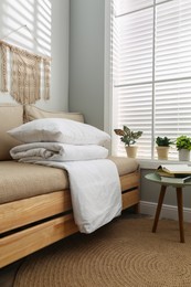Photo of Comfortable sofa with blanket near window indoors