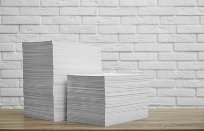 Photo of Stacks of paper sheets on wooden table. Space for text