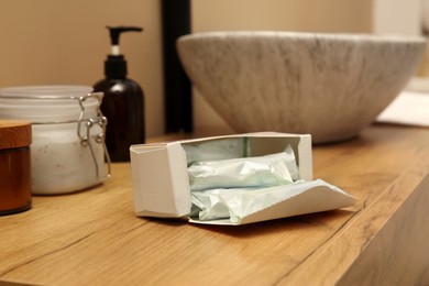 Photo of Package of tampons on wooden countertop in bathroom. Menstrual hygienic product