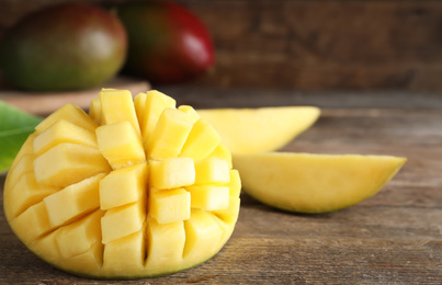 Photo of Cut fresh ripe mango on wooden table