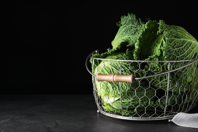 Fresh ripe savoy cabbages in metal basket on black table, space for text