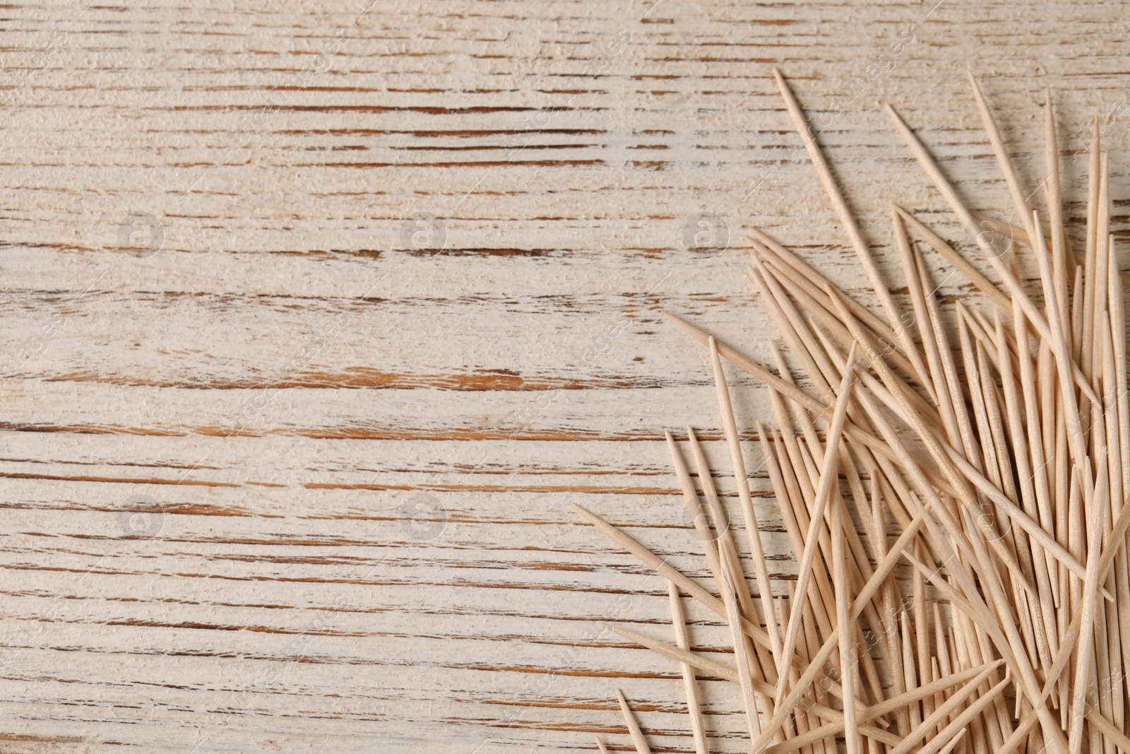 Photo of Disposable toothpicks on white wooden background, flat lay. Space for text