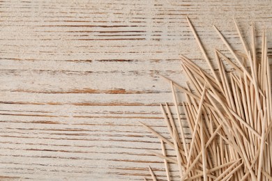 Disposable toothpicks on white wooden background, flat lay. Space for text