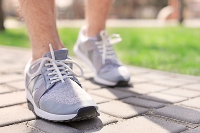 Photo of Sporty young man in training shoes outdoors, closeup