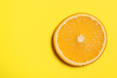 Photo of Slice of juicy orange on yellow background, top view. Space for text