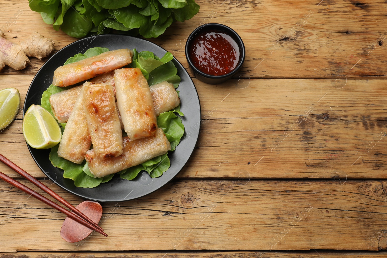 Photo of Tasty fried spring rolls served on wooden table, flat lay. Space for text