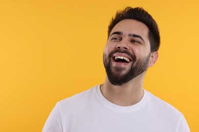 Photo of Handsome young man laughing on yellow background, space for text