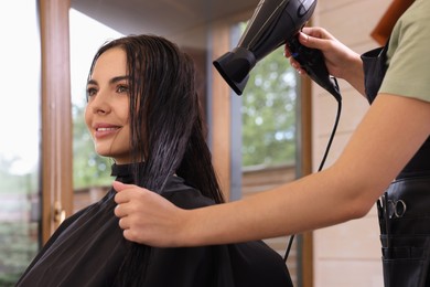 Photo of Hairdresser drying woman's hair in beauty salon