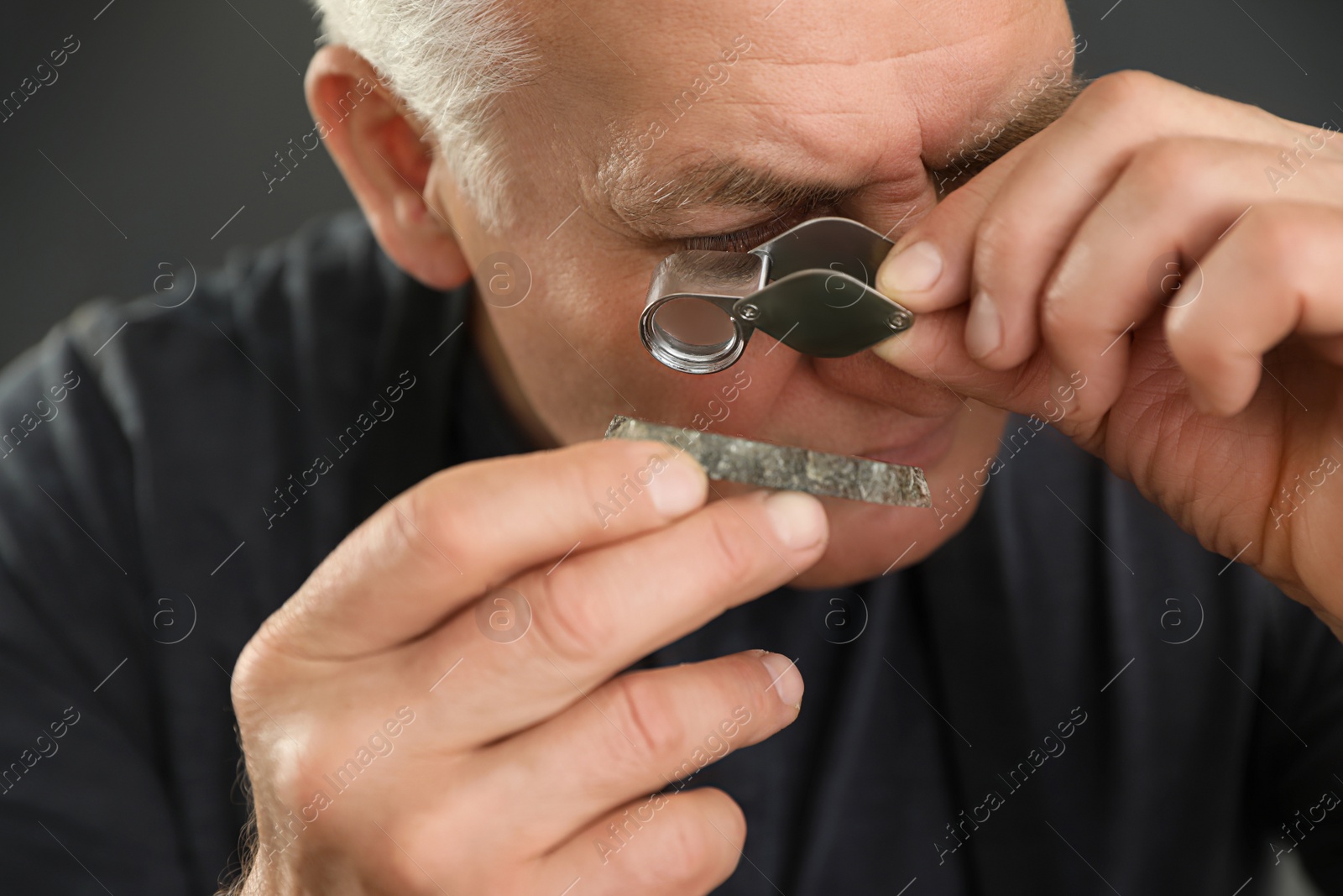 Photo of Male jeweler evaluating semi precious gemstone in workshop, closeup