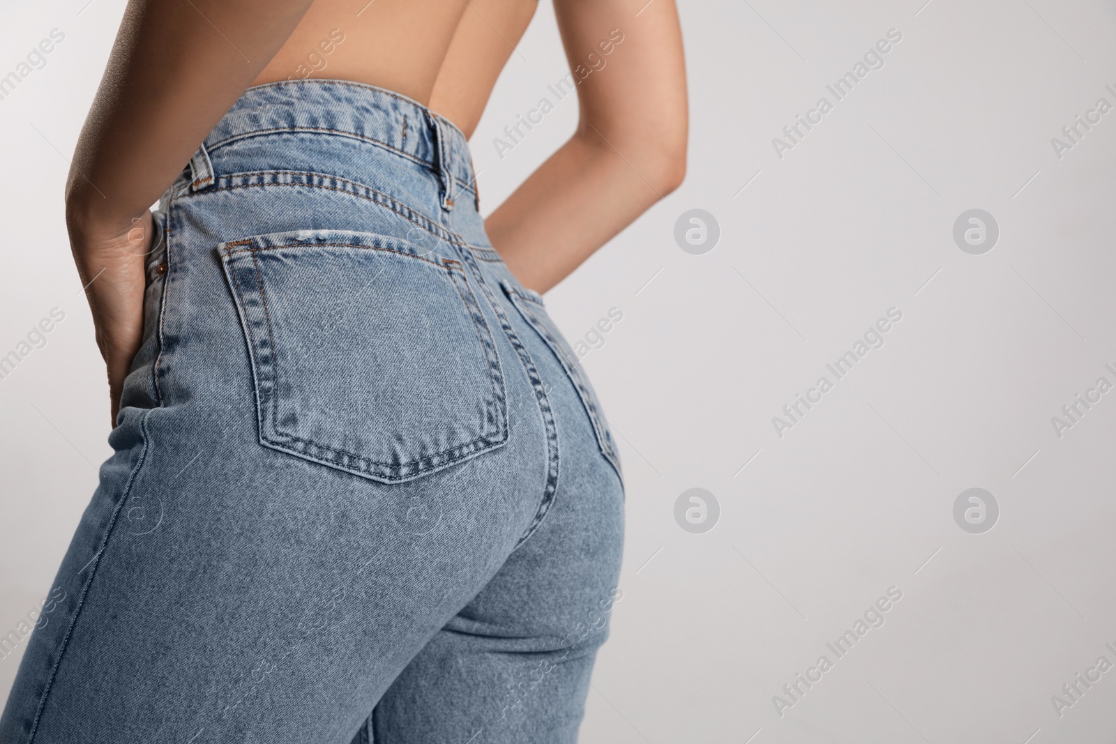 Photo of Woman in stylish jeans on light background, closeup. Space for text