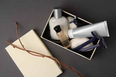 Box, different men's shaving accessories and dry branches on dark grey background, flat lay