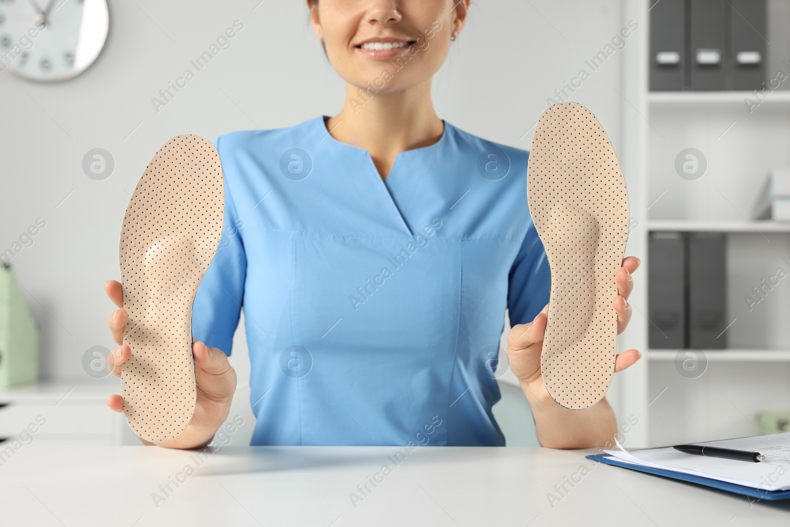 Photo of Female orthopedist showing insoles at table in hospital, closeup