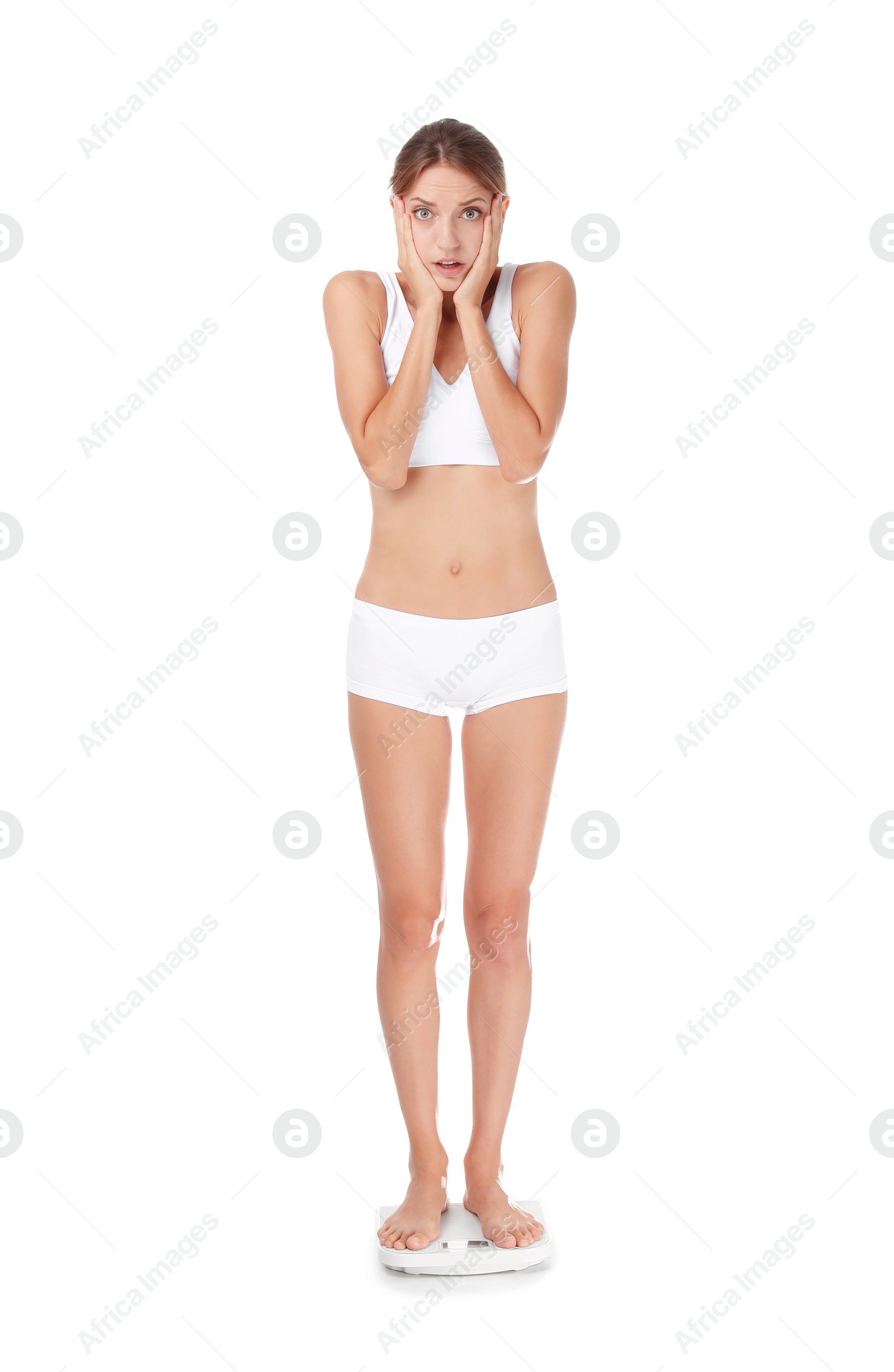 Photo of Worried young woman using bathroom scales on white background. Weight loss diet