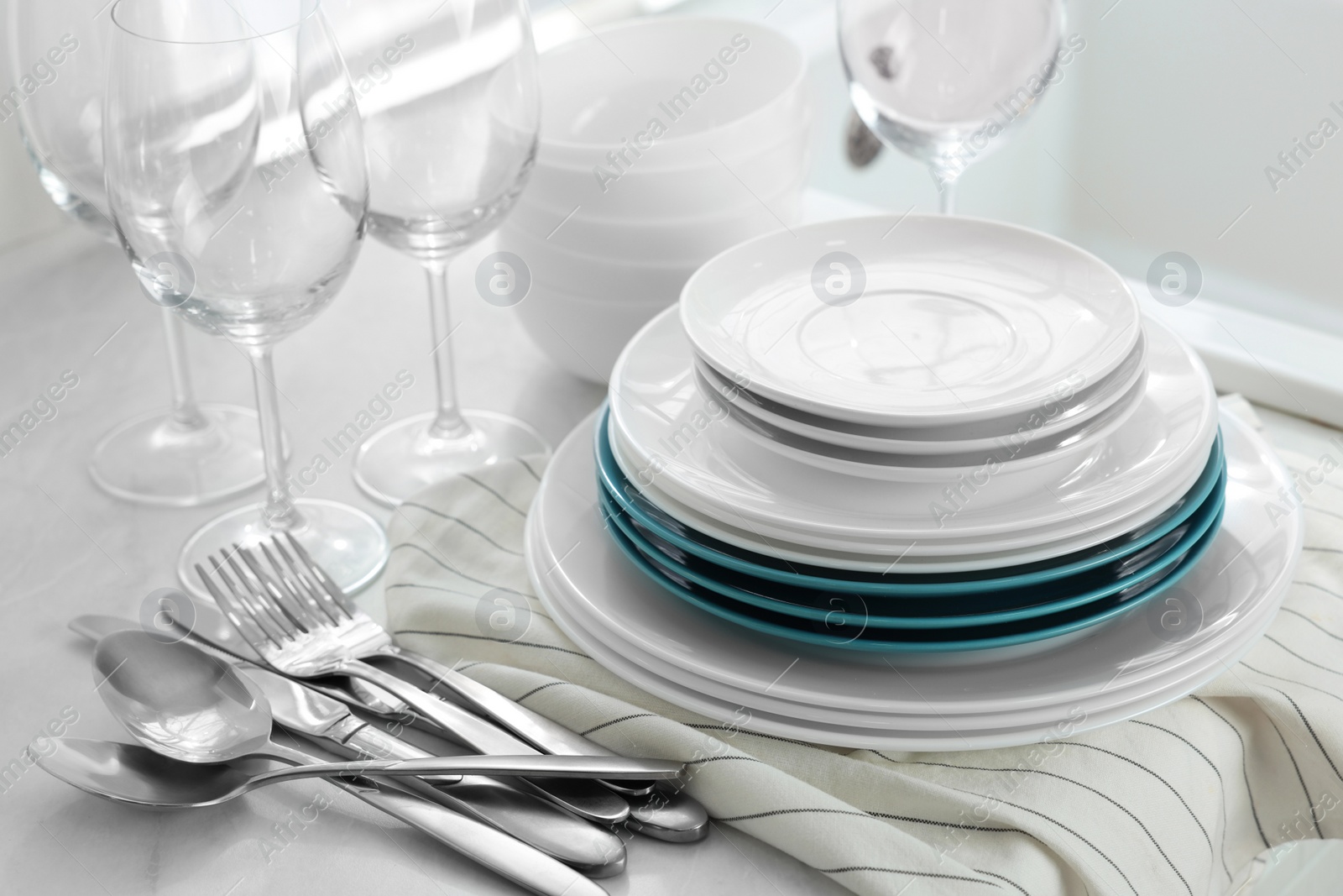 Photo of Different clean dishware, cutlery and glasses on countertop, closeup